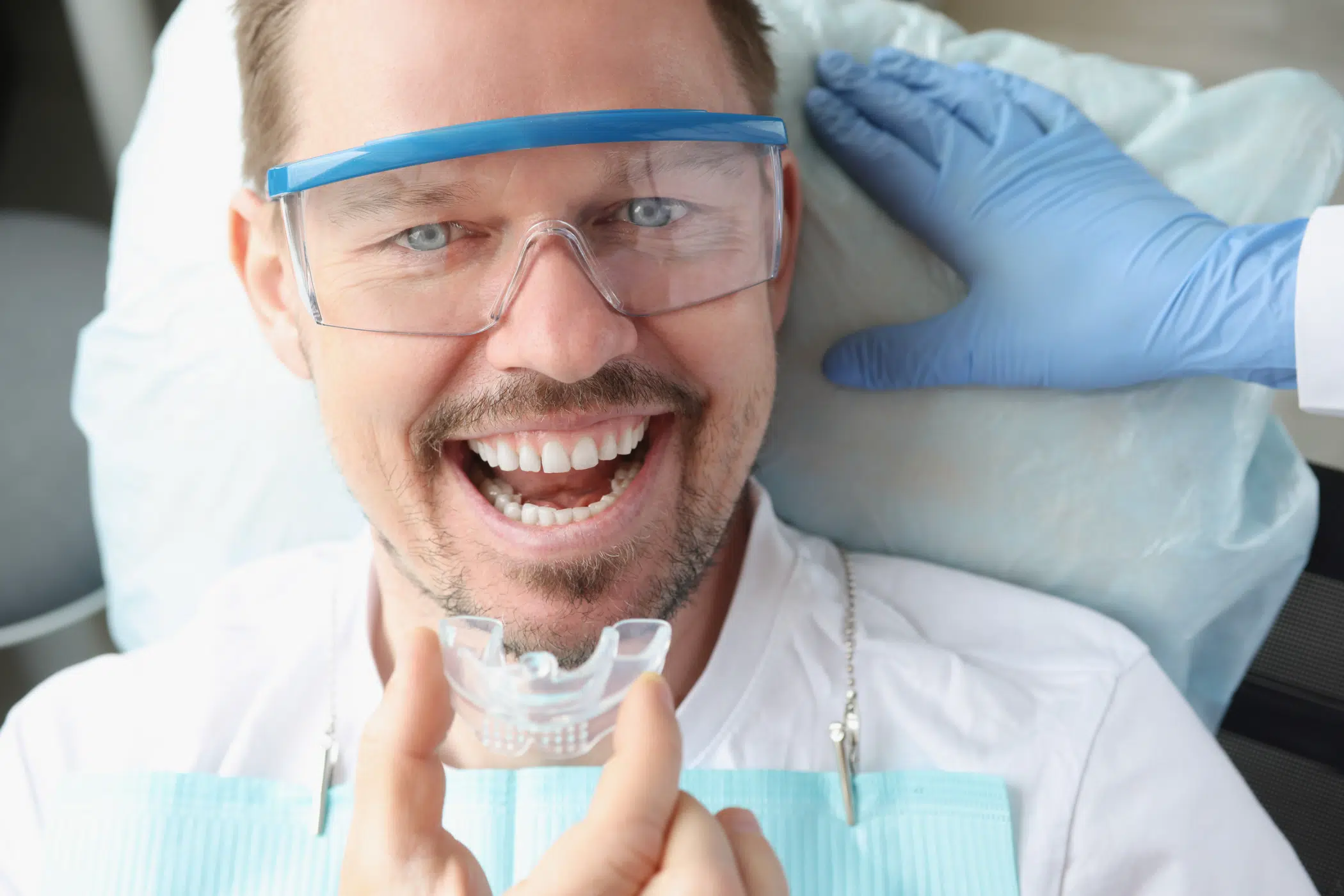 A dentist placing a Night Guard for Bruxism into male patients mouth