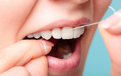 a person taking care of her teeth by flossing