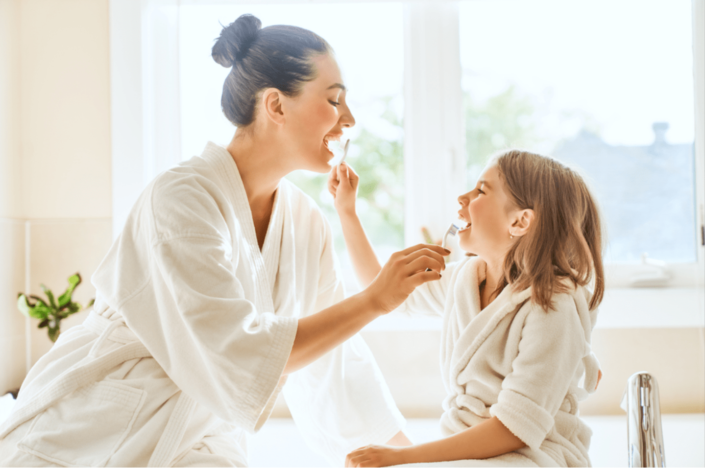 a woman and a child brushing each other's teeth