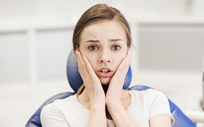 a woman holding the side of her cheeks because of dental related anxiety