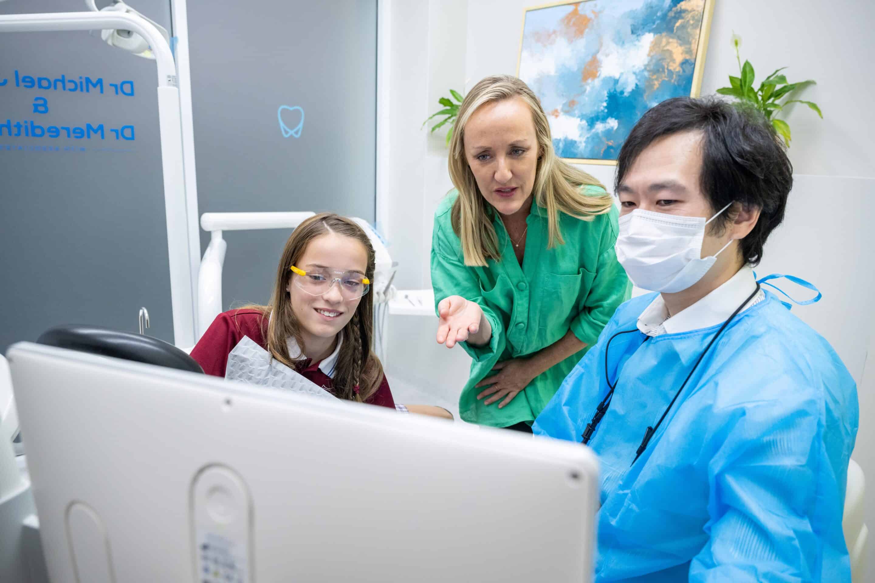 Dentist discussing teeth grinding with parent and child