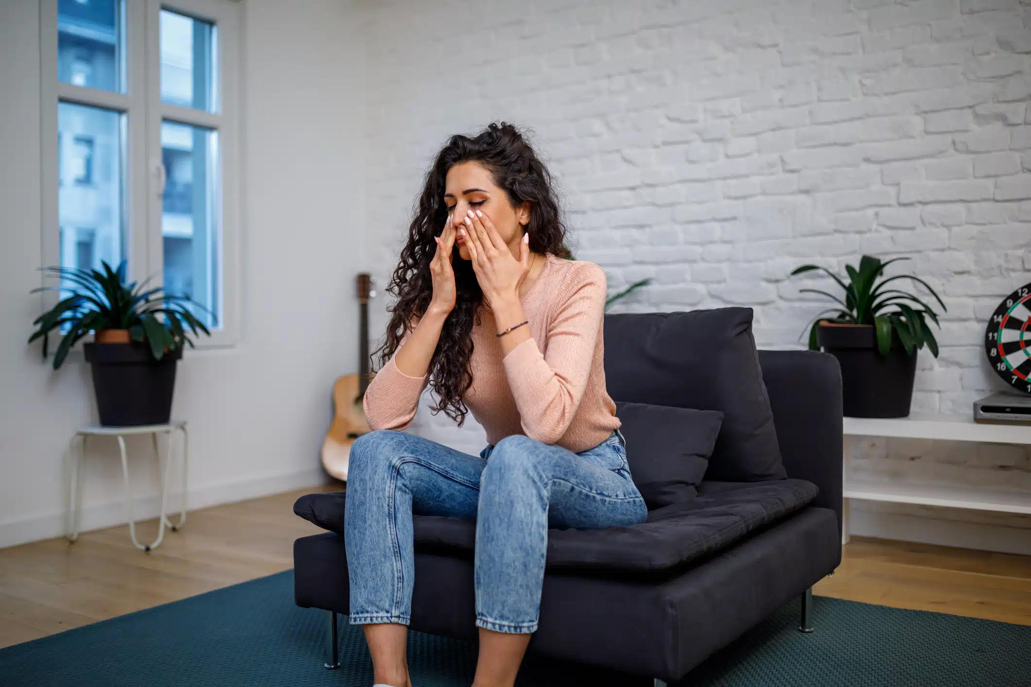 A young Caucasian woman is holding her hands to her painful sinuses causing a toothache.