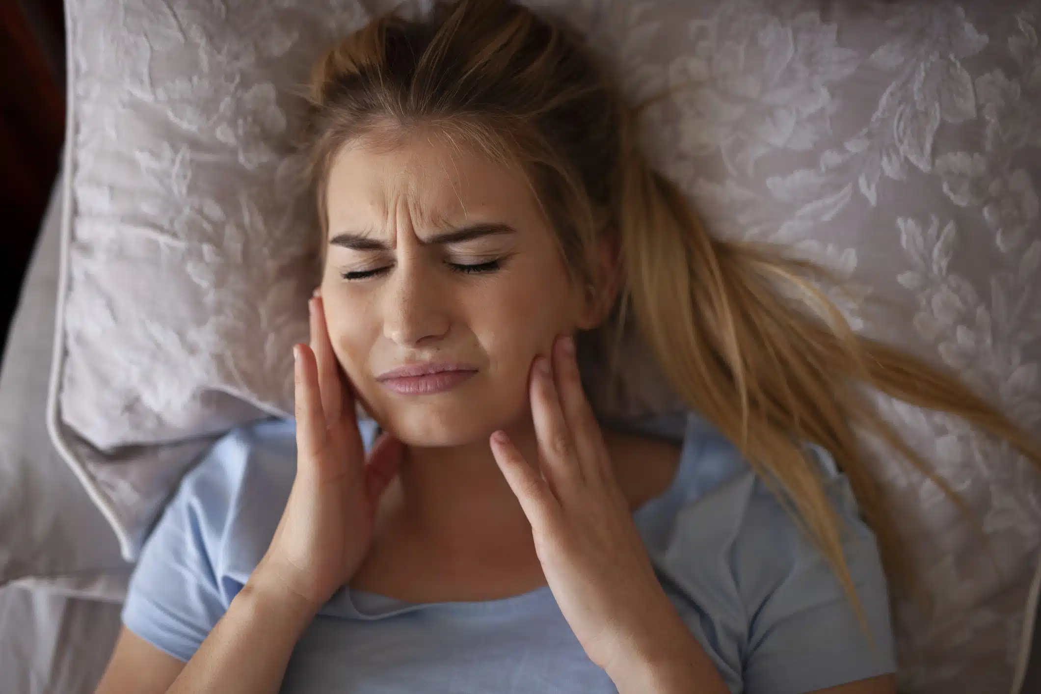 Woman with jaw pain in the morning due to teeth grinding (bruxism)