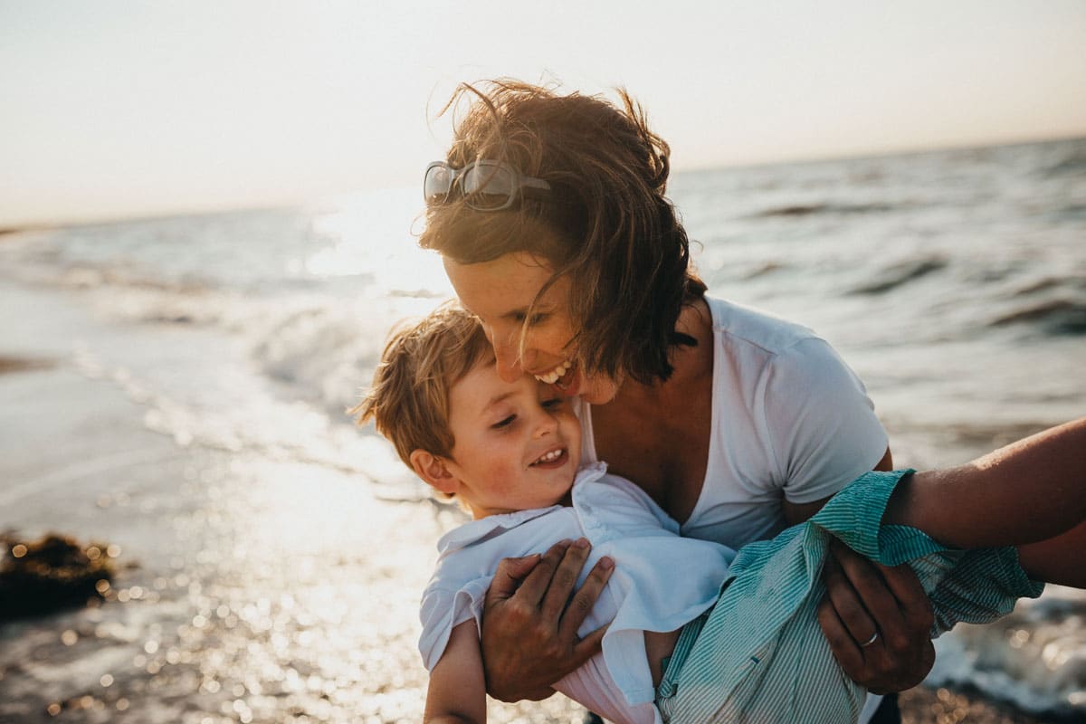 a mother holding her son while walking at the beach