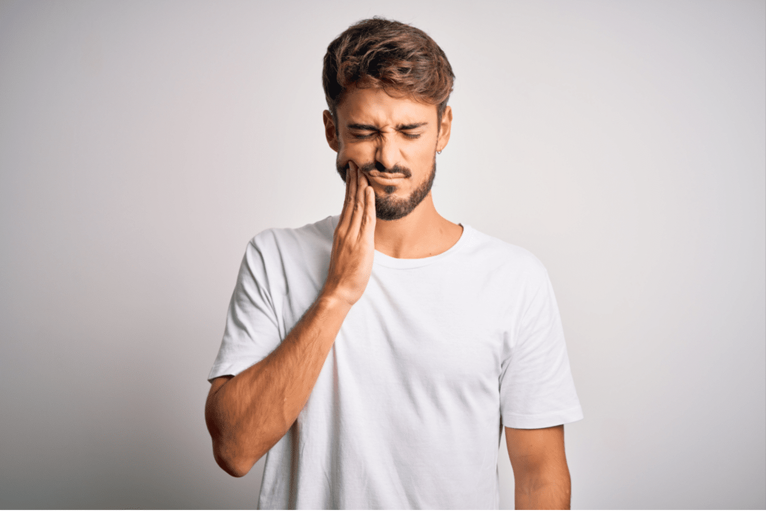 a man holding the side of his cheeks because of tooth pain